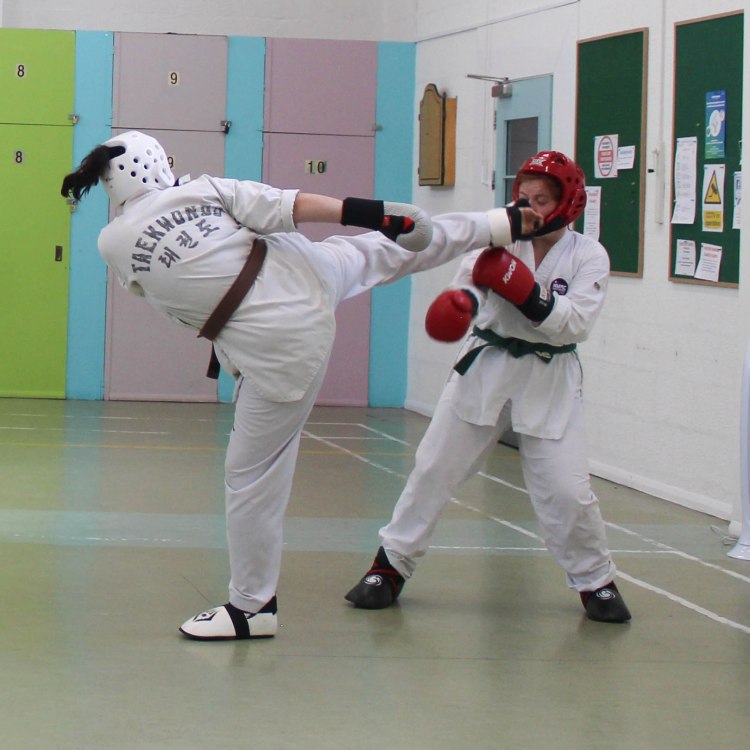 Female student scoring a roudnhouse kick in sparring